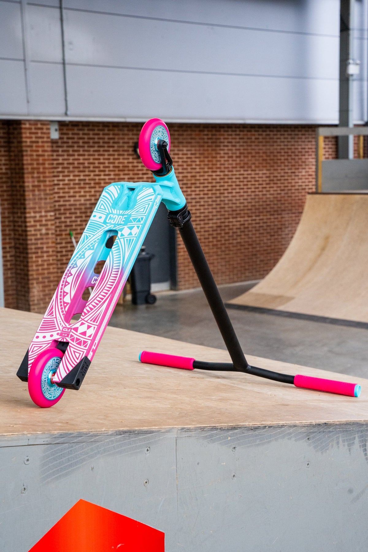 CORE CL1 complete stunt scooter in pink and teal - underside at skatepark